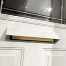 White front door with an open mail slot cover, revealing a wooden draft blocker or brush insert inside. The slot is positioned below a decorative glass window with metal framing