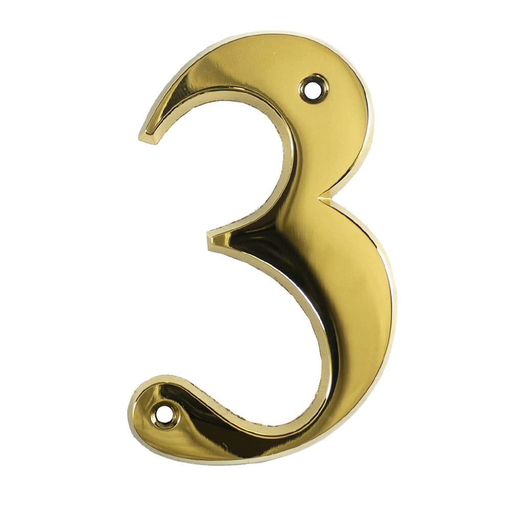 A gold-colored metal house number in the shape of the numeral 3.