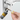 Hand inserting a key into a silver door lock while applying Home Secure graphite powder lubricant to the keyhole.