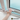 Child's hand operating a white sliding window restrictor lock on a UPVC frame, with a safety cable attached, light blue background, Home Secure logo in corner