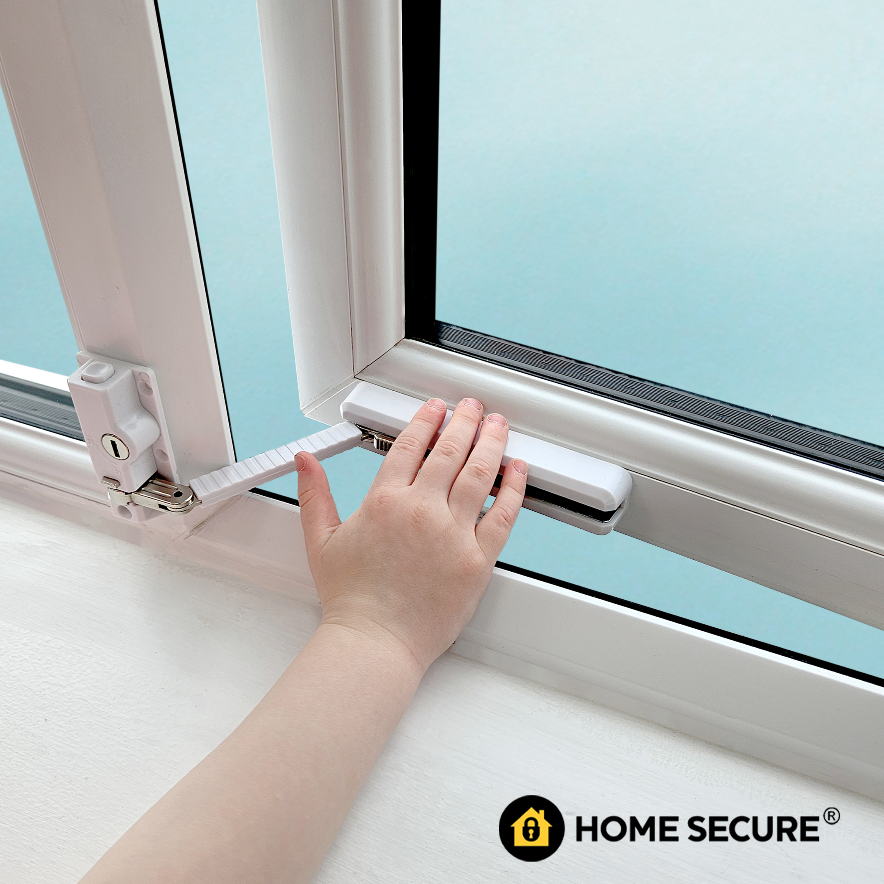 Child's hand operating a white sliding window restrictor lock on a UPVC frame, with a safety cable attached, light blue background, Home Secure logo in corner