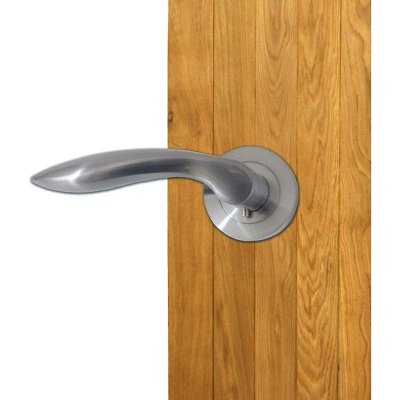 Curved satin chrome internal door handle mounted on a wooden door with round rose backplate.