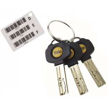 A set of three Yale dimple keys with black plastic heads attached to a metal keyring. Next to the keys is a white key code card labeled with the letters D, E, and F, each accompanied by a barcode and a numerical code beneath it.